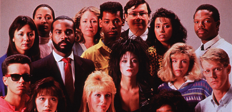 Color photograph of a multiracial group of people looking at the viewer.                                               