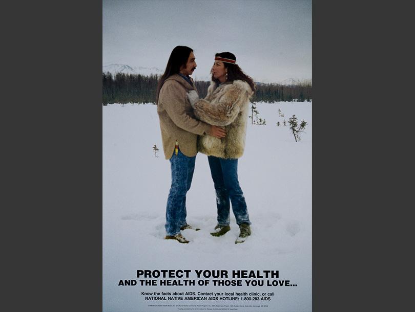 A poster with text and a color photograph of an Alaska Native man and woman embracing in a snow-covered field