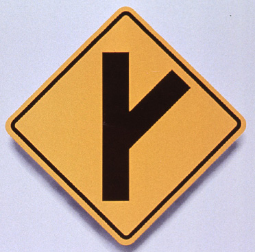 Yellow square road sign that has black line with another line branching off from it indicating branch in the roadway, above text