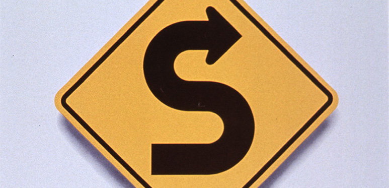 Yellow square road sign that has black curved arrow indicating curves in the roadway ahead above text