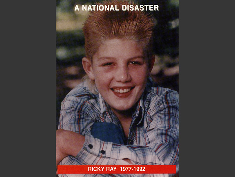 Fotografía a color de un niño blanco (Ricky Ray) sonriendo y sentado en el pasto