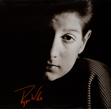 Fotografía en blanco y negro de un chico adolescente (Ryan White), que mira al frente y con media cara en sombra. Abajo a la izquierda se muestra su firma