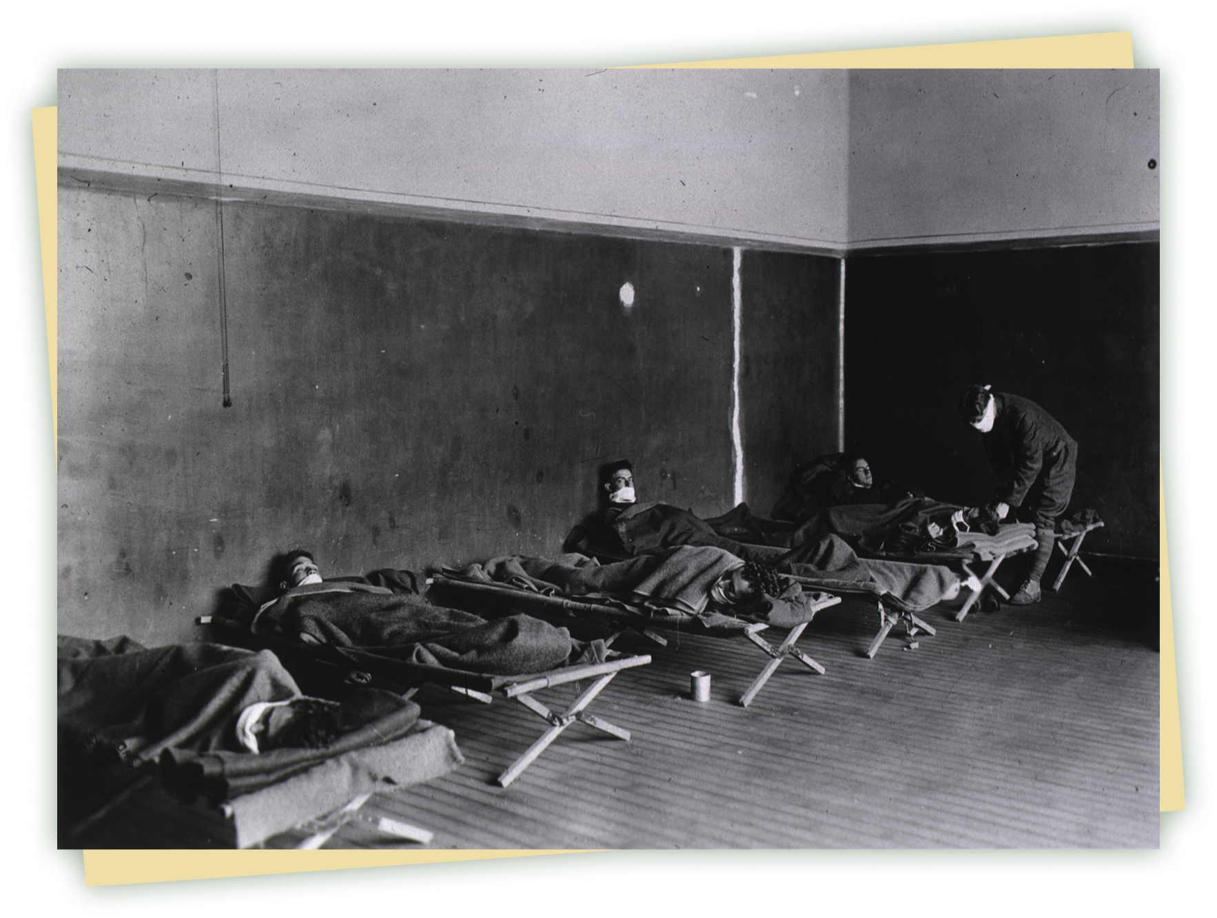 A black and white photograph of men lying on cots