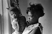 An African American woman holds a child.