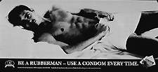 Black and white poster. Dominant visual image is a black and white photo reproduction featuring a young man lying in bed. Title below photo, accompanied by a Rubbermen logo and a small photo reproduction showing two condom packages. Publisher and sponsor information at bottom of poster.