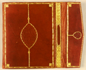 The lower cover and flap of MS A 7 featuring of red leather over pasteboards with envelope flaps. On the cover this is a deeply-impressed mandorla panel stamp whose inner field is filled with interlaced vines with flower-buds. The mandorla has a double gold-painted outline of shallow scallops; the points come together at the base of a bouquet of three small flowers from which a balustrade line extends to the frame. The frame is a tooled and gold-painted band of twisted double lines, and at each corner there is a stamped and gold-painted flower-bud. A similar frame occurs on the envelope flap, with a much smaller ovoid panel stamp. The fore-edge flap has a gold-stamped diaper pattern either side of an elongated cartouche.