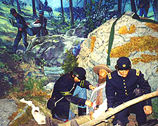 A color depiction two Civil War soldiers in blue dress uniforms caring for a wounded man in a rocky area of the woods.