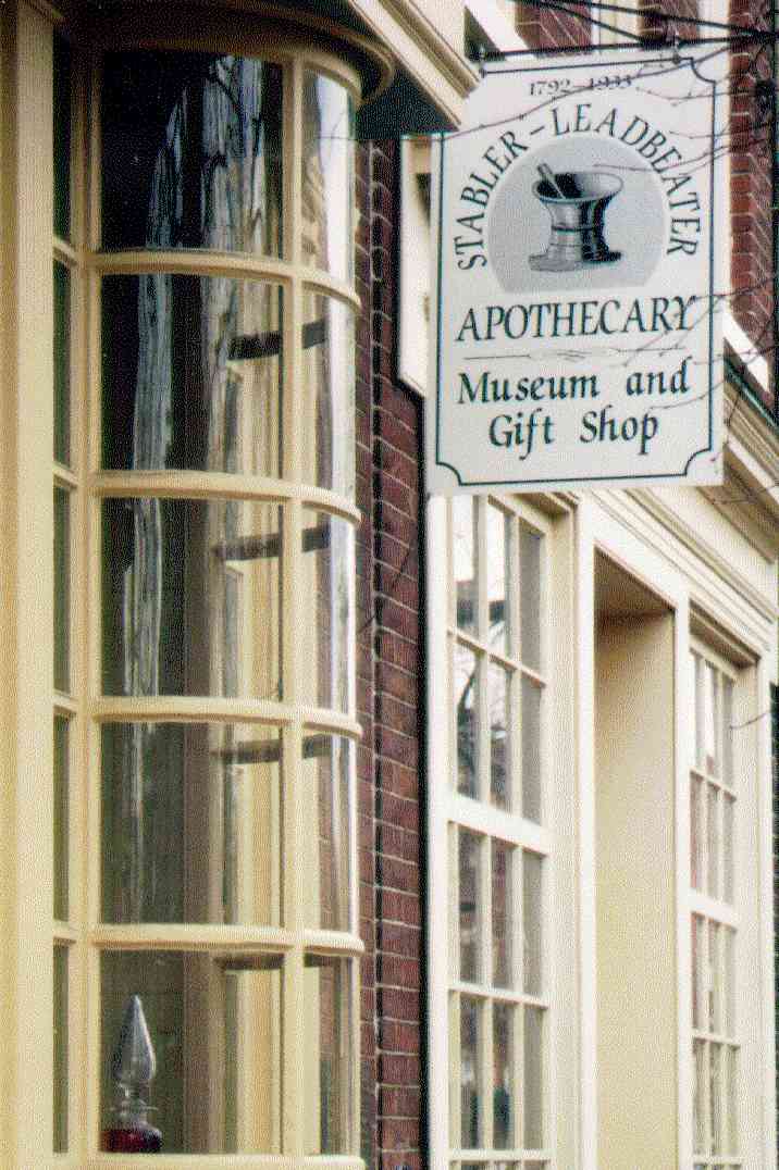 A color image of the entrance to the Apothecary Museum with hanging sign in front of a curved showcase window.