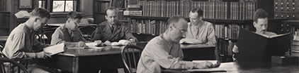 Men in uniform reading in a library.