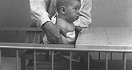 An infant is placed in a chair at a table.
