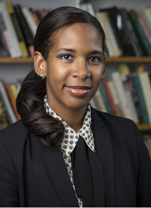 Informal photograph of a young Black woman in front of a bookcase.