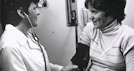 A woman takes a patient's blood pressure.
