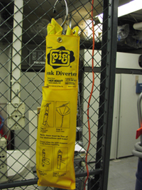A leak diverter is folded up and hanging on the fence of the disaster cage.  It is enclosed in a plastic pouch that includes instructions for assembly and use.