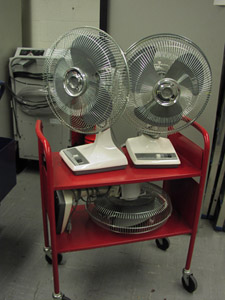 Three freestanding fans are sitting on a book cart, ready to be moved to a disaster location if necessary.