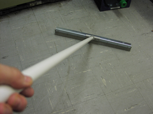 A squeegee with a long handle is being held in contact with the linoleum floor of a collection area.  The squeegee may be used to concentrate water in one area, so that it is easier to remove with a wet vac.
