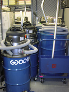 Four wet vacs are stored in the disaster cage area.  The electrical cords are wound neatly on top of the vacuums, and the attachment hoses are wound around the top, as well.  Additional accessories for each vacuum are nearby.
