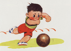 Slide showing a little boy with dark hair, wearing red shorts and a yellow and black shirt, approaching a red ball and pulling back his leg to kick it