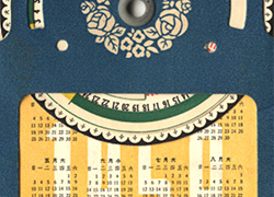 Front cover of a rectangular handheld calendar with dark blue border and yellow background and circular dial on top