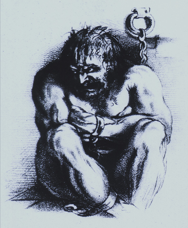 A powerfully built, angry looking man is sitting on the floor, arms folded and knees are drawn up close, his head is turned to the left; his wrists and ankles are in irons which are chained to the wall