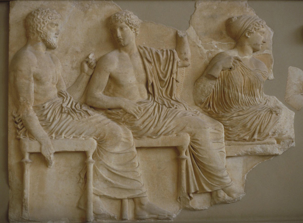 Photograph of a frieze of the Parthenon showing Apollo, seated, wearing a toga and facing left.