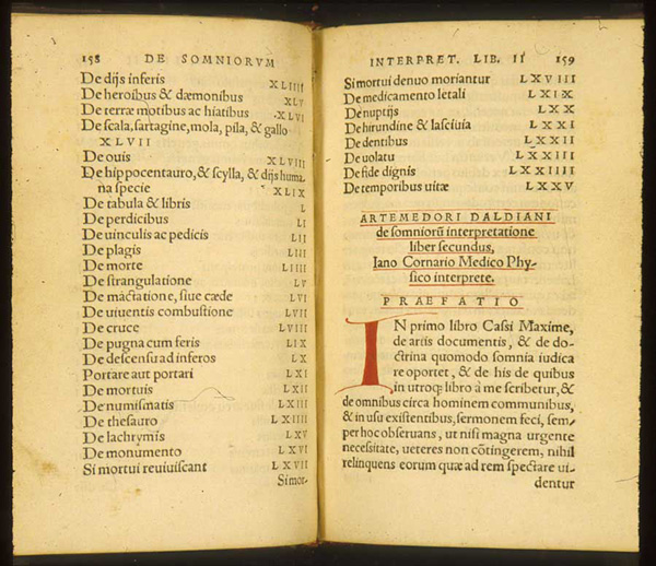 Book opened showing Latin text with manuscript initial letter 'I' in red ink