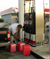 Fotografía de un hombre en una gasolinera llenando recipientes con gasolina