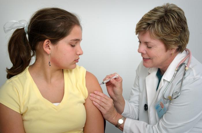 A nurse giving a vaccination in the arm of a young woman
