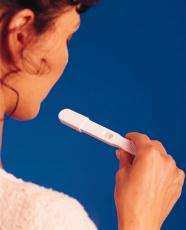 Photograph of a woman looking at an at-home pregnancy test
