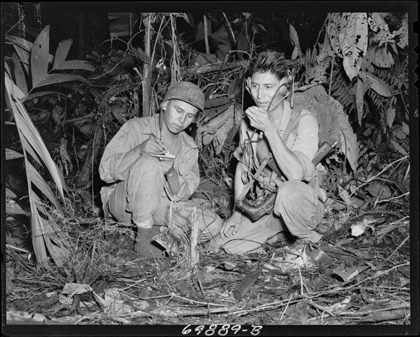 Black and white photograph of two Native American soldiers kneeling down while using a portable radio.