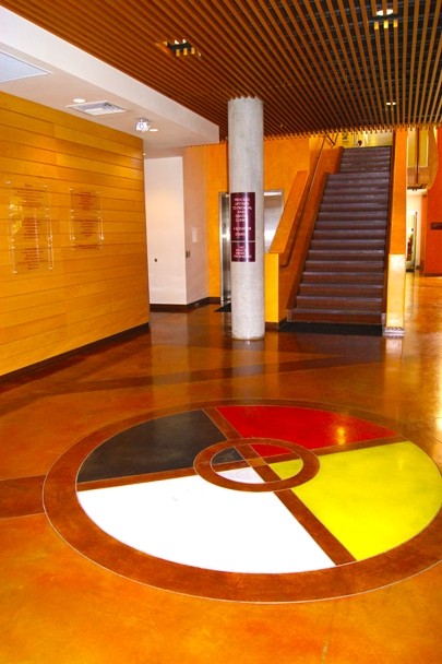 Color image of a building’s lobby. A large circular design painted on the floor can be seen in the foreground.