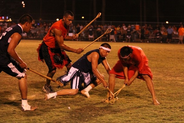 Color photograph of four young men playing in a stickball competition.