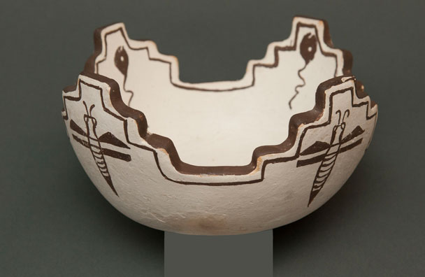Color image of a white, handmade bowl with designs on it painted in brown.