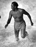 Black and white photograph of a man running out of the ocean.