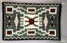 Color image of a handmade, embroidered rug, with various designs in darker colors.
