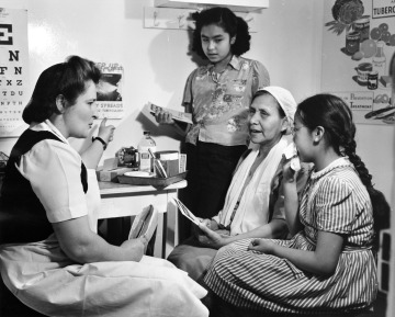 A nurse on the vessel Hygiene explains about Tuberculosis to an elderly woman and two young girls.